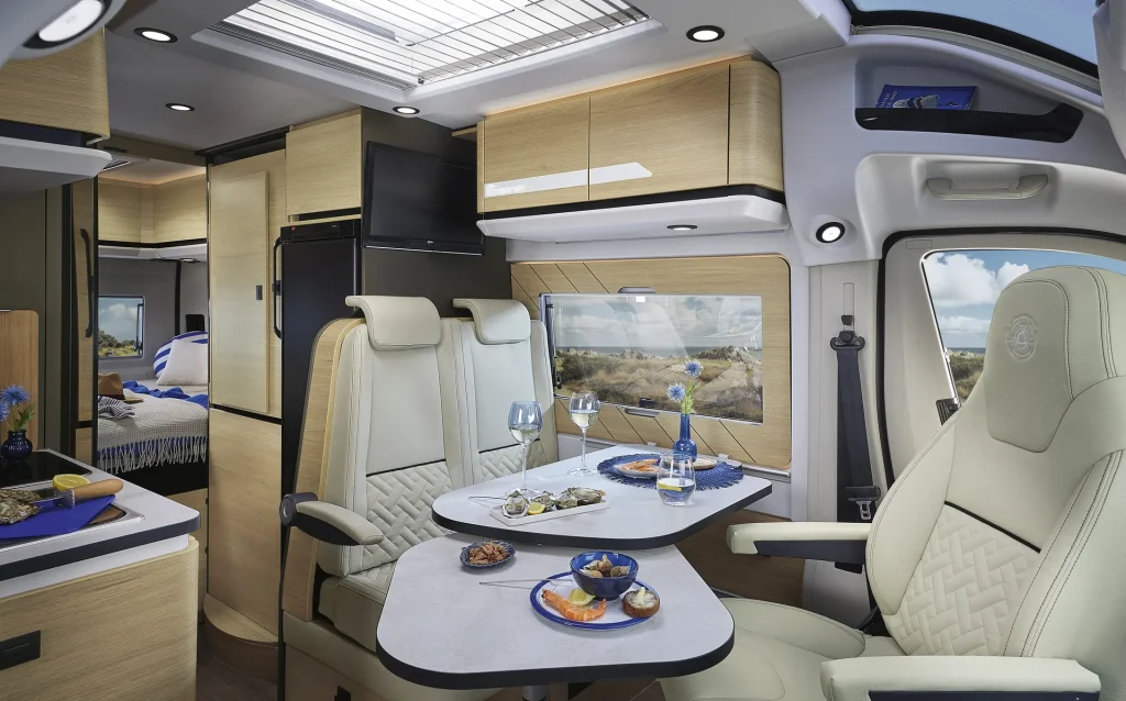 Salón de la furgoneta camper Dreamer D55 Select con los asientos de la cabina girados hacia la mesa